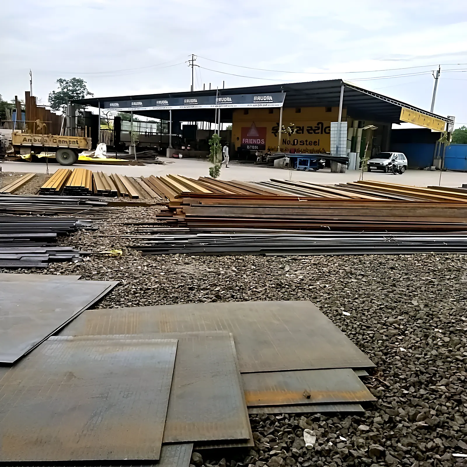 Steel plates, channels and sections stacked in the Thakkar Trading Co. yard on NH‑8, Bavla